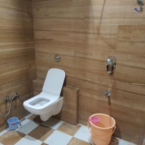 a bathroom with a toilet and a bucket in it at Golden Marigold Hotel in Jaisalmer