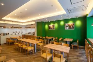 un restaurant avec des murs verts, des tables et des chaises en bois dans l'établissement Smile Hotel Hiroshima, à Hiroshima