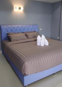Una cama azul con dos toallas blancas. en โคซี่ โฮมสเตย์ en Suan Phung