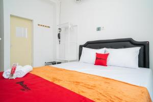 a bedroom with a large bed with a red blanket at RedDoorz @ Aralia Harapan Indah in Pulokendal