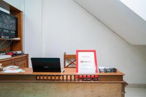 a desk with a laptop and a sign on it at RedDoorz @ Aralia Harapan Indah in Pulokendal
