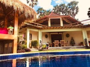 una casa con piscina frente a ella en Villa Cantik Sambirenteng en Gretek