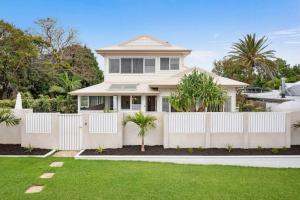 a white fence in front of a house at Fuller Holidays - Hacienda, Luxury 5 bedroom home with pool in Byron Bay