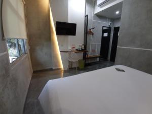 a bedroom with a white bed and a television at Rid's Hotel Palembang in Talang Kelapa