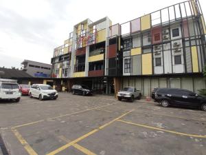un estacionamiento con autos estacionados frente a un edificio en Rid's Hotel Palembang, en Talang Kelapa