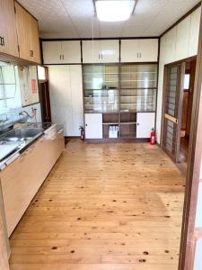 a large kitchen with a wooden floor and cabinets at 格安素泊まり宿南郷駅徒歩3分好立地の一軒家丸々貸しサイクルシーズン南郷 in Meitsu
