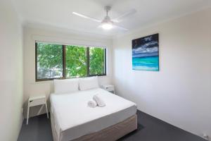 a white bedroom with a bed and two windows at Noosa Shores Resort in Noosa Heads