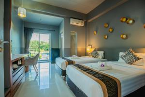 a hotel room with two beds and a desk at The Rubber Hotel - SHA Extra Plus in Thalang