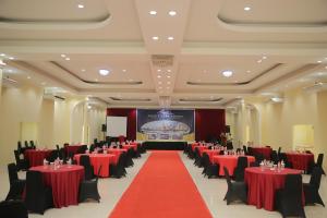 a banquet hall with red tables and chairs and a screen at Rid's Hotel Palembang in Talang Kelapa