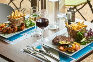 una mesa con dos platos de comida y copas de vino en Kyriad Direct Lyon Sud - Chasse-Sur-Rhône en Chasse-sur-Rhône