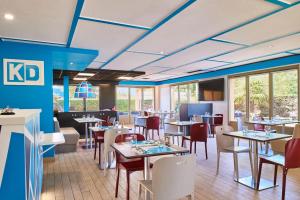 a dining room with tables and chairs and windows at Kyriad Direct Lyon Sud - Chasse-Sur-Rhône in Chasse-sur-Rhône