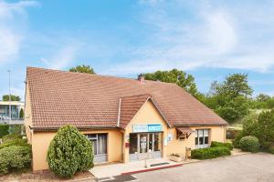 a small yellow building with a brown roof at Kyriad Direct Lyon Sud - Chasse-Sur-Rhône in Chasse-sur-Rhône