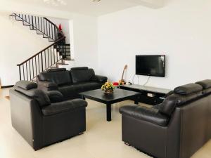 a living room with black leather furniture and a piano at Cinnamon Villa in Matara