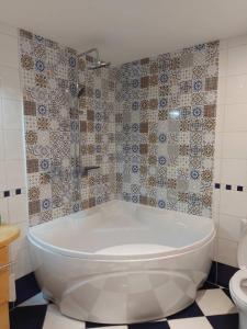 a white bath tub in a bathroom with a toilet at Center Firefly Danube Apartment in Novi Sad
