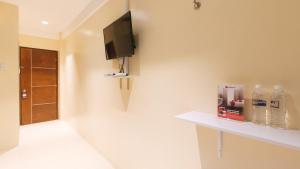 a bathroom with a tv on a wall with bottles of water at RedDoorz at Laiya Vivo Hotel Batangas in San Juan