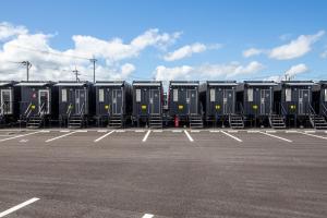 eine Reihe tragbarer Toiletten auf einem Parkplatz in der Unterkunft HOTEL R9 The Yard Miyakonojo in Miyakonojō