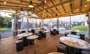 a restaurant with tables and stools in a room with windows at Pool and Villa Sorang in Jeju