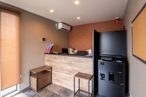 a kitchen with a counter and a black refrigerator at HOTEL R9 The Yard Miyakonojo in Miyakonozyō