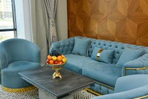 a blue couch with a bowl of fruit on a table at Ramada by Wyndham Turkistan in T&uuml;rkistan