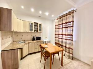 una pequeña cocina con mesa de madera y sillas en Sarai-Batu Guest House, en Atyraū