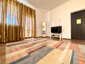 a living room with a large window and a flat screen tv at Sarai-Batu Guest House in Atyrau