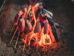 a bunch of sausages on sticks on a grill at Kominkayado LOOF Shonoie in Minobu