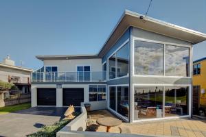 ein Haus mit großen Glasfenstern und einer Terrasse in der Unterkunft Sandy Cove in Port Fairy