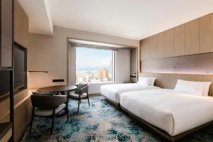 广岛Hilton Hiroshima的一间有两张床、一张桌子和一扇窗户的酒店房间