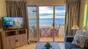 a living room with a television and a view of the ocean at Del Rae Unit 8 25 Shoal Bay Road in Shoal Bay