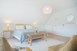 a white bedroom with a bed and a table at A Coque'Line in Frasnes-lez-Anvaing