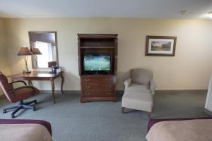 Habitación de hotel con TV, escritorio y silla en Swan Lake Resort, en Plymouth