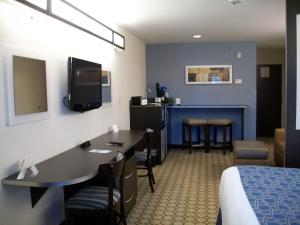 a hotel room with a bed and a desk with chairs at Microtel Inn & Suites by Wyndham Spring Hill/Weeki Wachee in Weeki Wachee