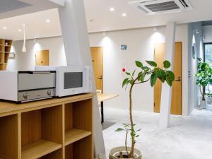 a living room with a microwave and a plant at Denpaku Amami Hotel in Amami