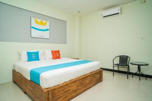 um quarto com uma cama e uma cadeira em Sans Hotel Zam-Zam Syariah Palangkaraya em Palangkaraya