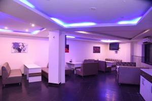 a waiting room with tables and chairs and purple lights at Hotel Gaurab Near Railway Station in Dehradun