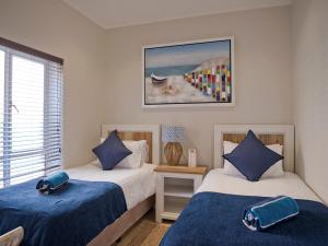 een slaapkamer met 2 bedden met blauwe lakens bij Umdloti Holiday Resort Apartments in Umdloti