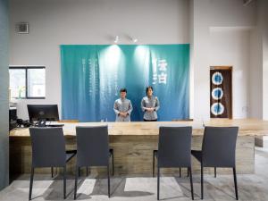two men are standing at a table in a room at Denpaku Amami Hotel in Amami