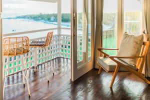a room with a balcony with chairs and a window at Sea La Vie Resort Nusa Penida in Nusa Penida