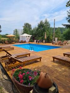 einem Pool mit Bänken und einem Blumenkorb in der Unterkunft "Garaske Breze" Kućice za izdavanje sa bazenom in Aranđelovac