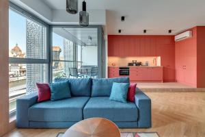 a living room with a blue couch and a kitchen at Downtown Apartments Granaria Premium Riverside & Parking in Gdańsk