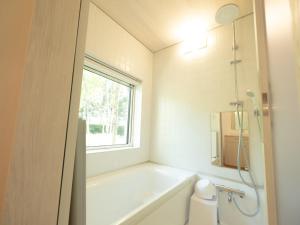 La salle de bains est pourvue d'une baignoire, de toilettes et d'une fenêtre. dans l'établissement Coboushi オモヤ, à Niseko