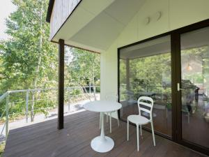 une table blanche et deux chaises sur une terrasse dans l'établissement Coboushi オモヤ, à Niseko