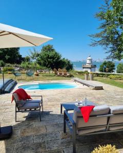 a pool with chairs and a table and an umbrella at Le Manoir des Impressionnistes - Bord de Mer in Honfleur