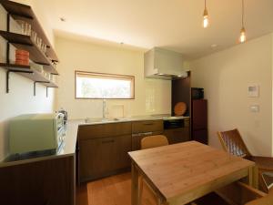 a kitchen with a wooden table and a kitchen with a sink at Coboushi ハナレ in Niseko