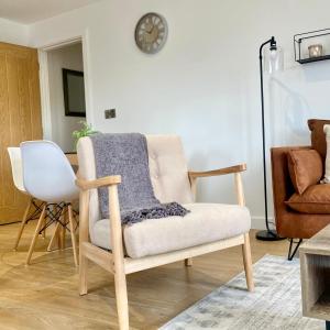 a living room with a chair and a clock on the wall at Modern 2 Bed Apartment/Free Parking/Near City/Self-Check In in Handsworth