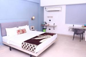 a bedroom with a bed and a table and a desk at Virohaa Garden Hotel in Ghaziabad