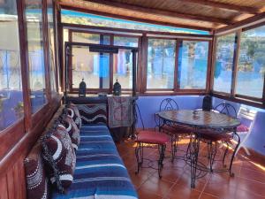 Una habitación con una mesa y sillas y ventanas. en Dar layla moulati, en Chefchaouen
