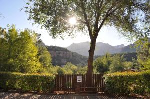 una valla de madera con un árbol y montañas en el fondo en La Petite Sedona en Sedona