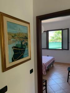 a painting of a boat on a wall next to a bedroom at A Casa di Nonna in Bosa