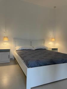 1 cama blanca en un dormitorio con 2 luces en Seashell Guest House, en Torre Marino